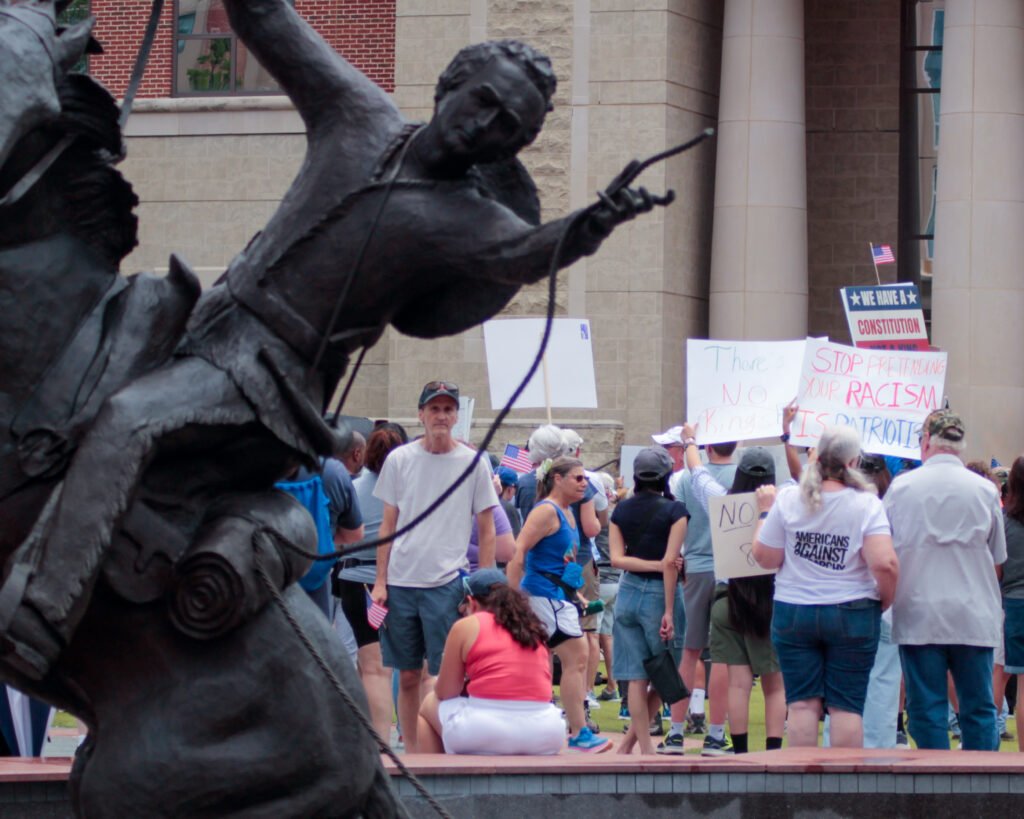 statue in foreground and people and signs in the background